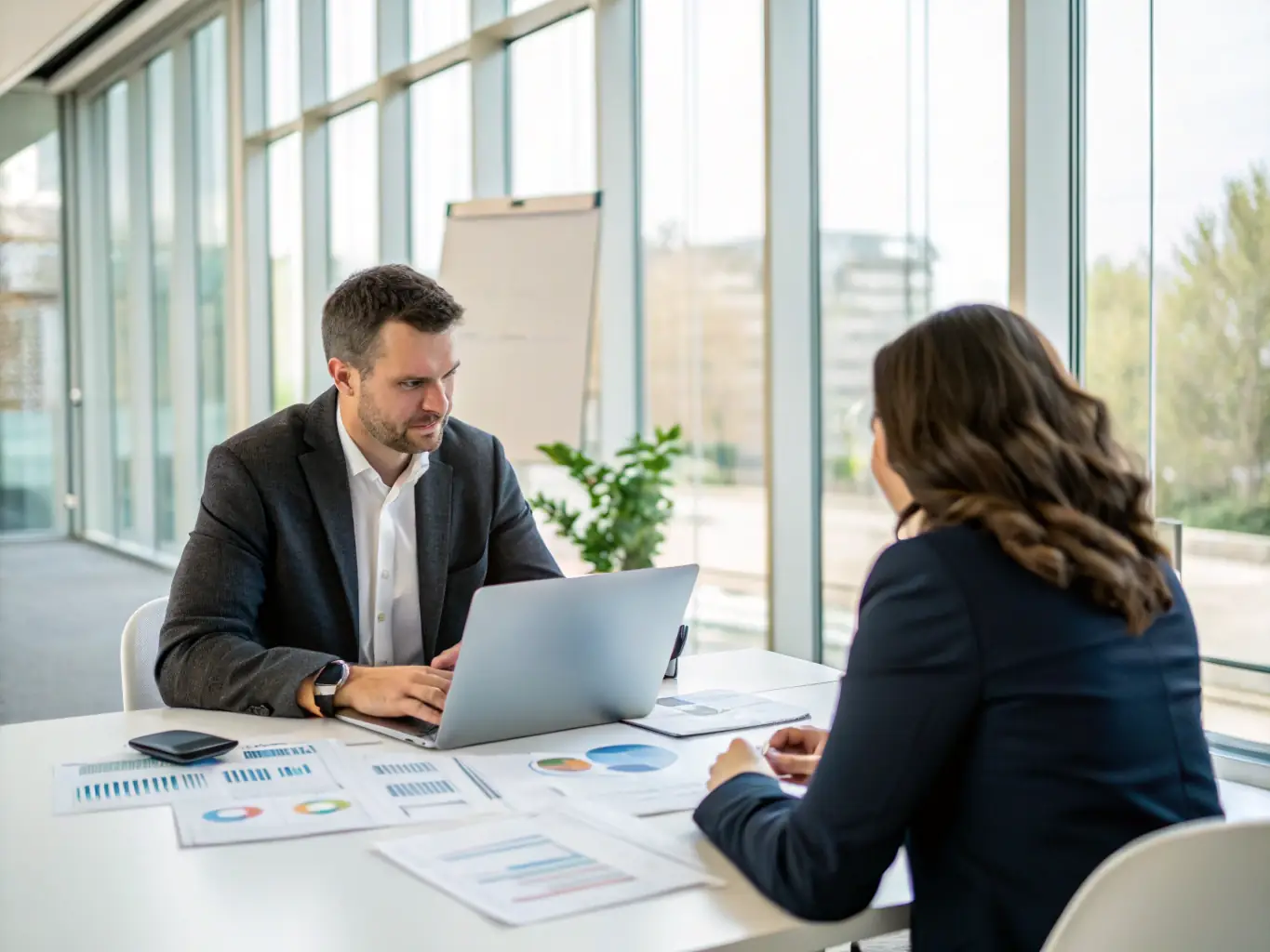 A consultant sitting at a desk, reviewing communication strategies with a client in a modern office setting, emphasizing a collaborative and professional environment.